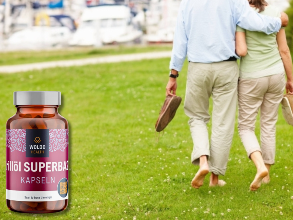 Senior couple walking barefoot on grass near a marina, with a bottle of Woldo Health Krillöl Superba2 capsules shown in the foreground, symbolizing active lifestyle and vitality.